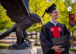 Student smiling in cap and gown holding diploma